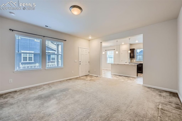 unfurnished living room featuring baseboards and light colored carpet