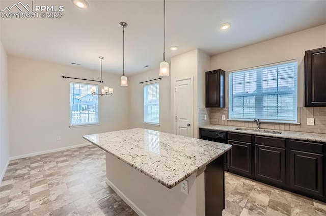 kitchen with a sink, decorative backsplash, a kitchen island, light stone countertops, and recessed lighting
