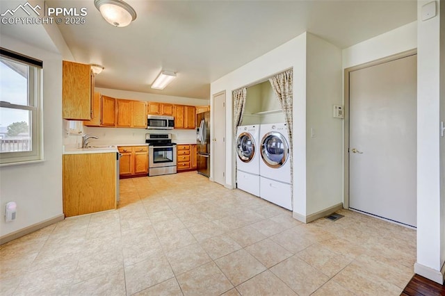 1120 Pipestone Ct, Colorado Springs, CO 80911 - kitchen featuring appliances with stainless steel finishes, separate washer and dryer, light countertops, brown cabinets, and baseboards