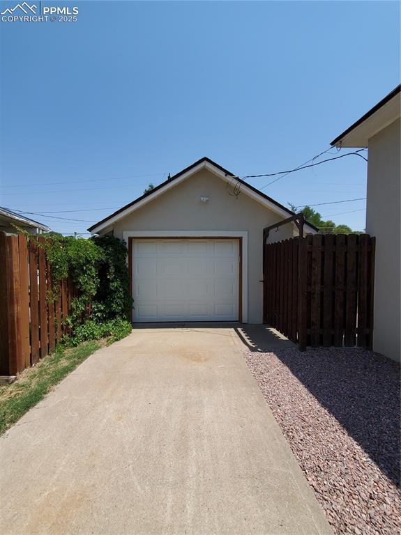 detached garage with fence and concrete driveway