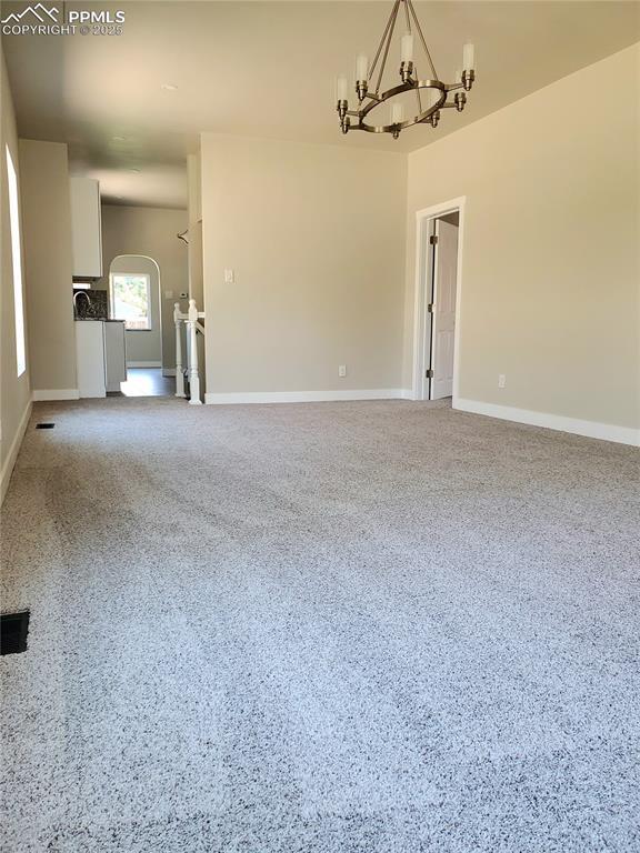 spare room featuring an inviting chandelier and baseboards