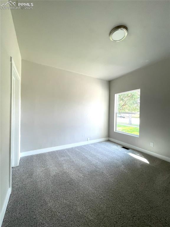 spare room featuring carpet floors, baseboards, and visible vents