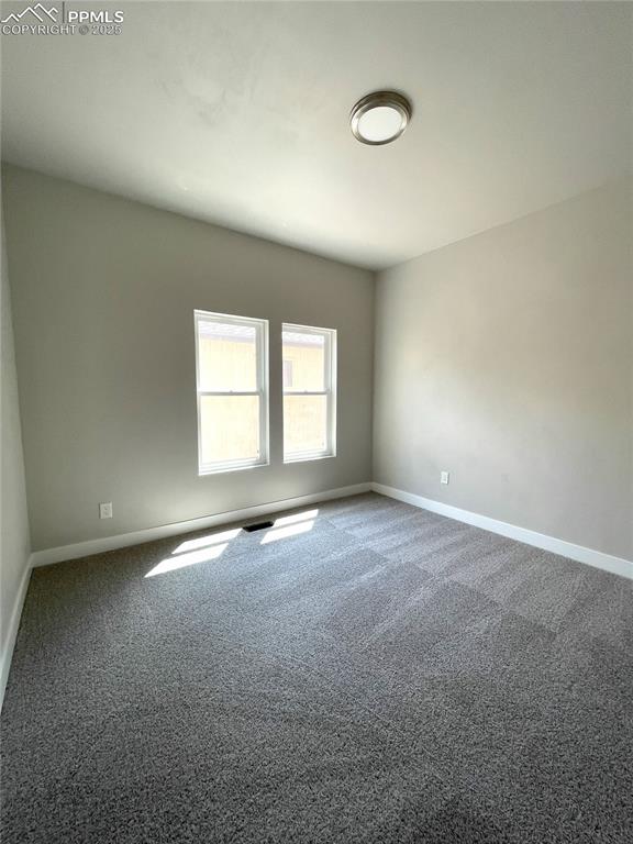 carpeted empty room featuring baseboards and visible vents