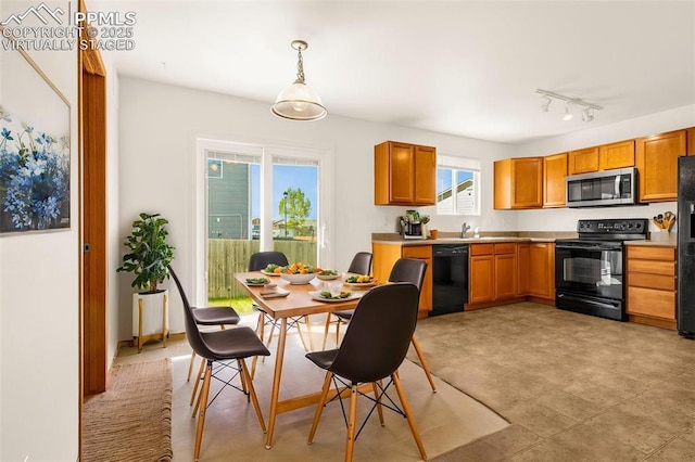 kitchen featuring black appliances, light countertops, hanging light fixtures, brown cabinetry, and track lighting