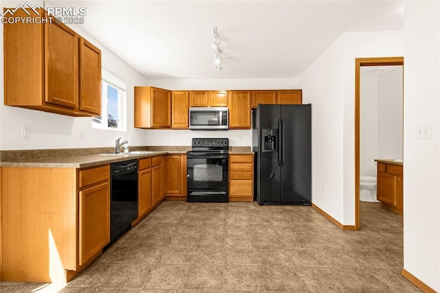 kitchen featuring black appliances, a sink, brown cabinets, and baseboards