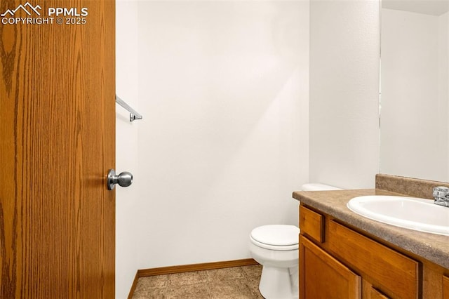 bathroom featuring toilet, baseboards, and vanity