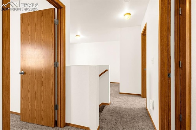 corridor featuring an upstairs landing, carpet, and baseboards