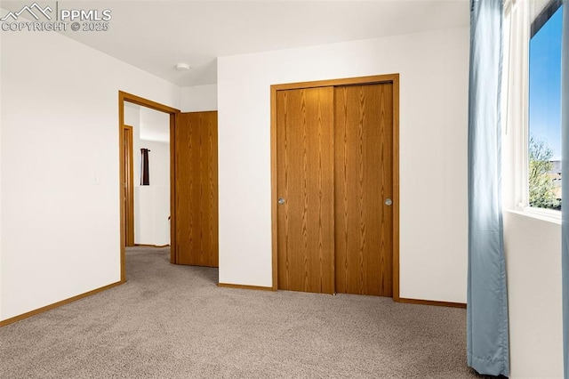 unfurnished bedroom featuring carpet, a closet, and baseboards