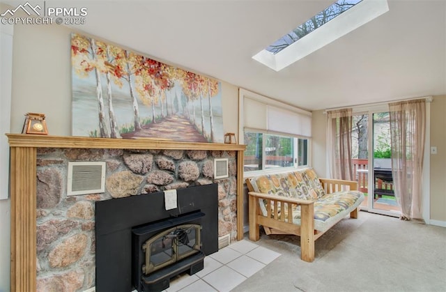 living area featuring baseboards, carpet flooring, visible vents, a wood stove, and a skylight