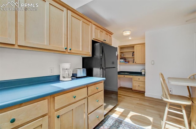 kitchen featuring light wood-style flooring, freestanding refrigerator, open shelves, light brown cabinets, and built in study area