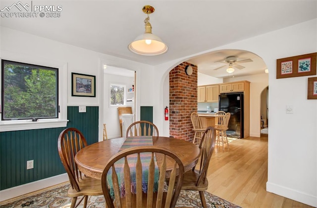 dining room with ceiling fan, arched walkways, baseboards, and light wood-type flooring