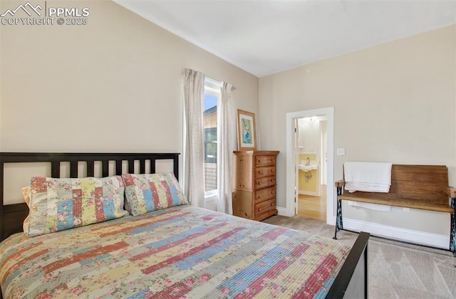 bedroom with ensuite bathroom, baseboards, and carpet floors