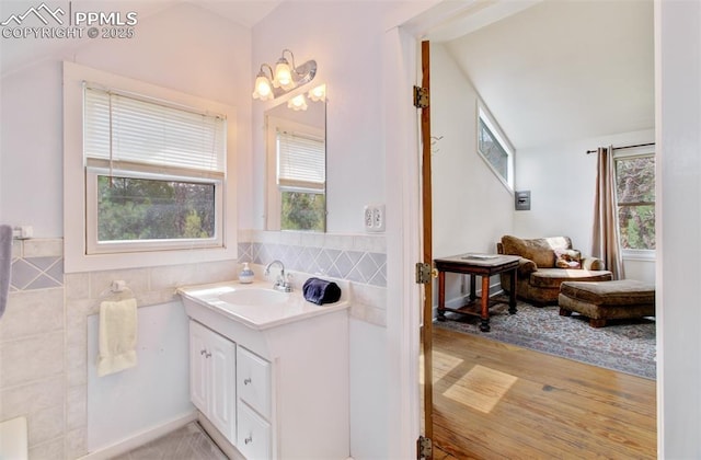 bathroom with tile walls, vanity, and wood finished floors