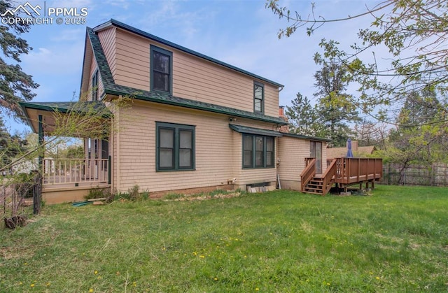 back of property featuring fence, roof with shingles, a deck, and a lawn