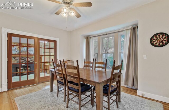 dining area with baseboards, light wood-style flooring, and a ceiling fan