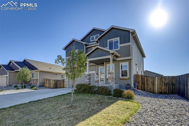 view of front of home with concrete driveway, board and batten siding, a front lawn, and fence
