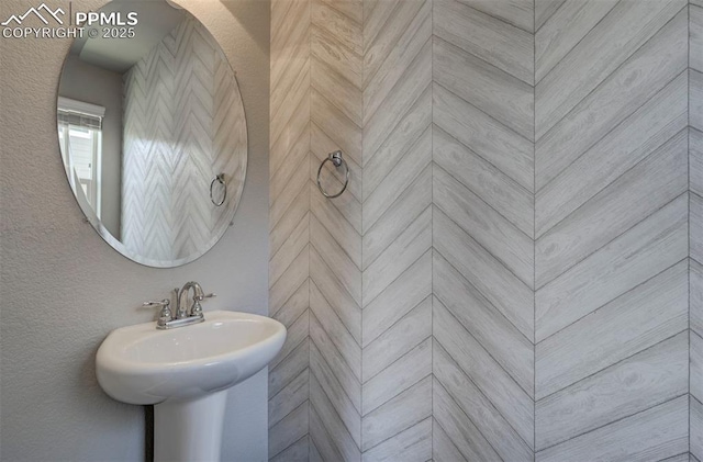 bathroom featuring tiled shower and a sink