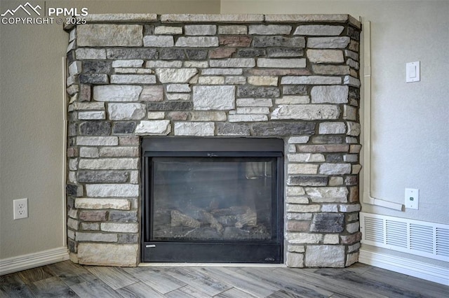 interior details featuring wood finished floors, visible vents, baseboards, and a fireplace