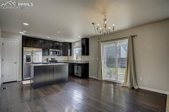 kitchen with a kitchen island, dark wood-style flooring, baseboards, appliances with stainless steel finishes, and a chandelier
