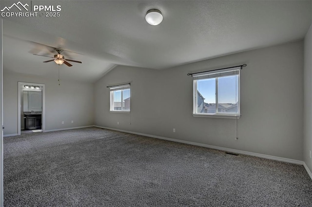 empty room featuring lofted ceiling, carpet, baseboards, and a ceiling fan