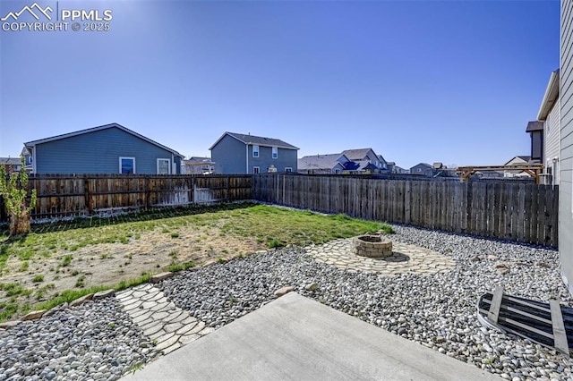 view of yard featuring a fenced backyard, a fire pit, and a residential view