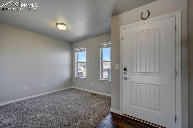 entryway with a textured ceiling, baseboards, and visible vents