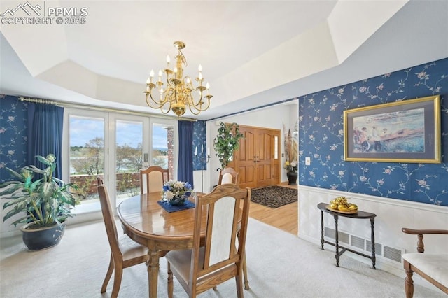 dining area with wallpapered walls, a chandelier, a tray ceiling, a wainscoted wall, and carpet flooring