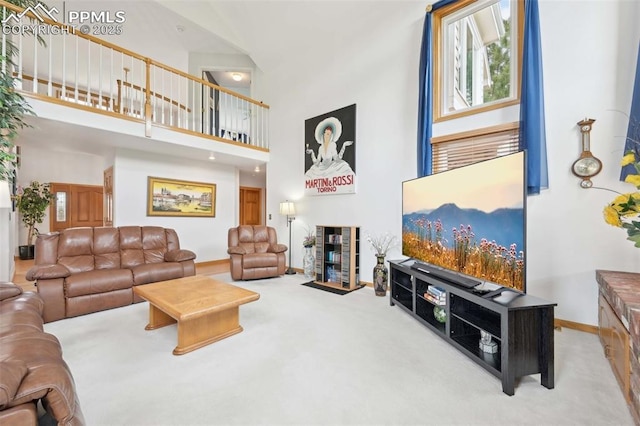 carpeted living area featuring a high ceiling and baseboards