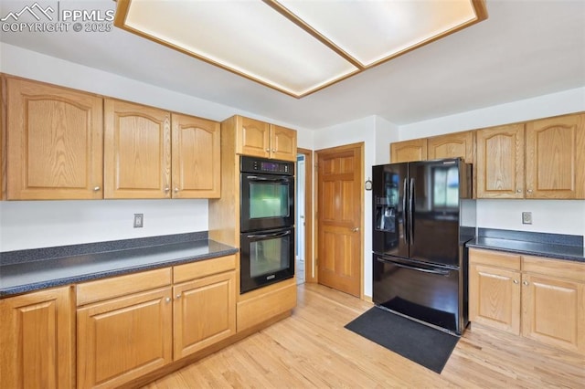 kitchen with black appliances, dark countertops, and light wood finished floors