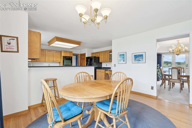dining area with a chandelier, light wood finished floors, and baseboards