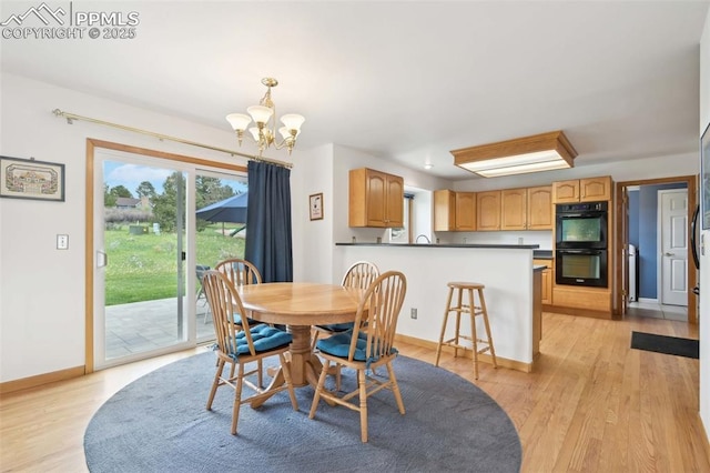 dining space with a chandelier, light wood finished floors, and baseboards