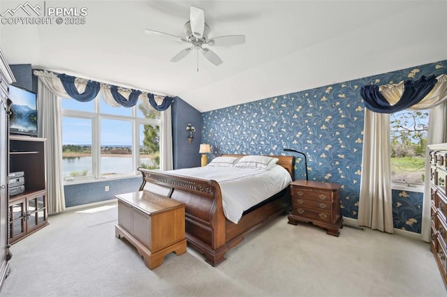 carpeted bedroom with wallpapered walls, lofted ceiling, a water view, and ceiling fan