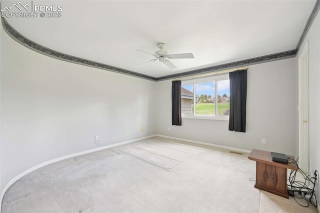 carpeted empty room featuring a ceiling fan and baseboards