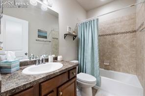 10150 Bracknell Pl, Peyton, CO 80831 - bathroom with toilet, vanity, and shower / bath combo with shower curtain