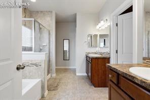 10150 Bracknell Pl, Peyton, CO 80831 - full bath with a stall shower, a garden tub, two vanities, and baseboards