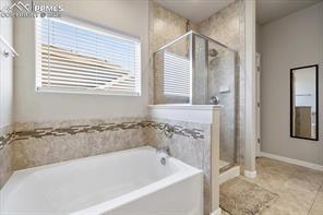 10150 Bracknell Pl, Peyton, CO 80831 - bathroom with a garden tub, a shower stall, and tile patterned flooring
