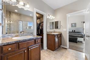 10150 Bracknell Pl, Peyton, CO 80831 - bathroom featuring a shower stall, two vanities, and tile patterned flooring