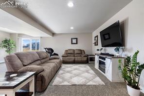 10150 Bracknell Pl, Peyton, CO 80831 - carpeted living area with a glass covered fireplace and recessed lighting