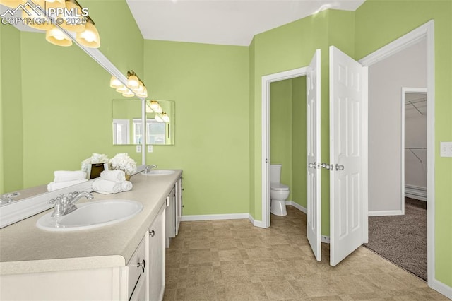 12383 Pine Valley Cir, Peyton, CO 80831 - bathroom featuring toilet, double vanity, baseboards, and a walk in closet