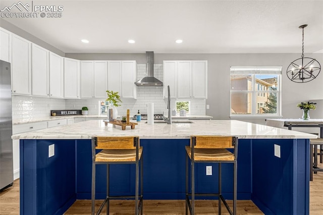 12383 Pine Valley Cir, Peyton, CO 80831 - kitchen with wall chimney range hood, light wood finished floors, tasteful backsplash, and recessed lighting