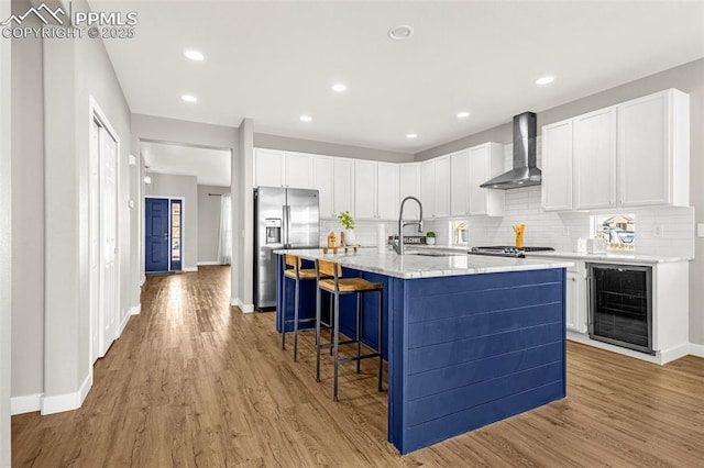 12383 Pine Valley Cir, Peyton, CO 80831 - kitchen with wall chimney range hood, beverage cooler, a sink, stainless steel fridge, and decorative backsplash