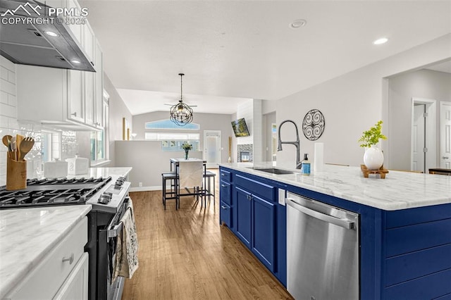 12383 Pine Valley Cir, Peyton, CO 80831 - kitchen with stainless steel appliances, extractor fan, a sink, blue cabinets, and wood finished floors