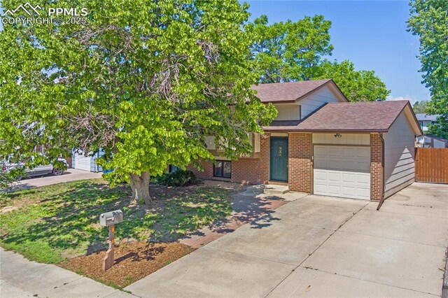 1430 Commanchero Dr, Colorado Springs, CO 80915 - tri-level home with a garage, concrete driveway, brick siding, and a shingled roof