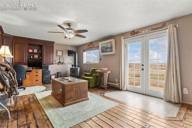 17090 Forest Green Way, Elbert, CO 80106 - home office with french doors, a ceiling fan, a textured ceiling, a wood stove, and baseboard heating