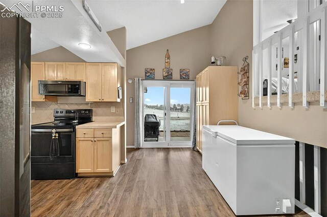 17090 Forest Green Way, Elbert, CO 80106 - kitchen with black microwave, electric range oven, vaulted ceiling, light brown cabinets, and wood finished floors