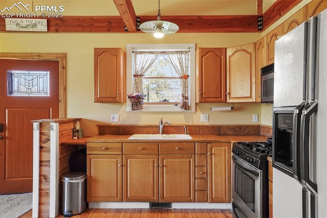 18 Fountain Pl, Manitou Springs, CO 80829 - kitchen featuring white fridge with ice dispenser, a sink, stainless steel gas range oven, beam ceiling, and hanging light fixtures