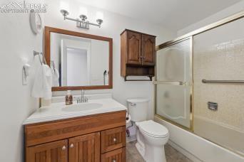 5050 Bunk House Ln, Colorado Springs, CO 80917 - bathroom with toilet, vanity, and shower / bath combination with glass door