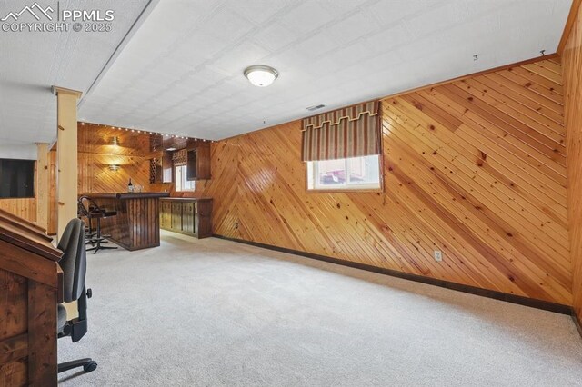 5050 Bunk House Ln, Colorado Springs, CO 80917 - unfurnished living room featuring a bar, wooden walls, and carpet floors