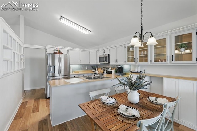 5050 Bunk House Ln, Colorado Springs, CO 80917 - kitchen with appliances with stainless steel finishes, vaulted ceiling, a peninsula, light countertops, and glass insert cabinets