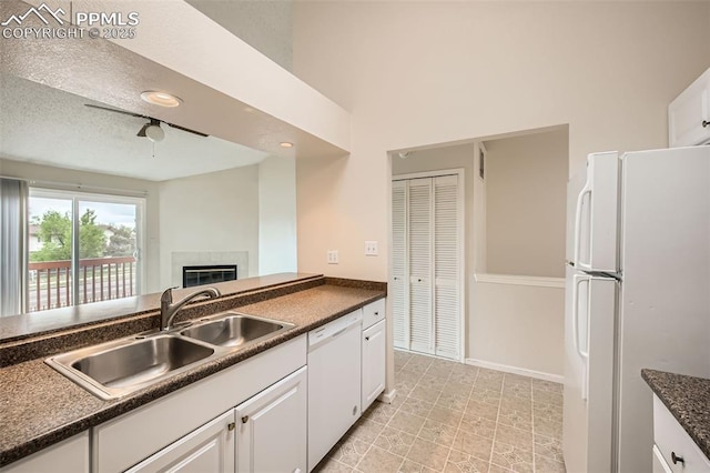 kitchen featuring dark countertops, white cabinetry, a sink, and white appliances